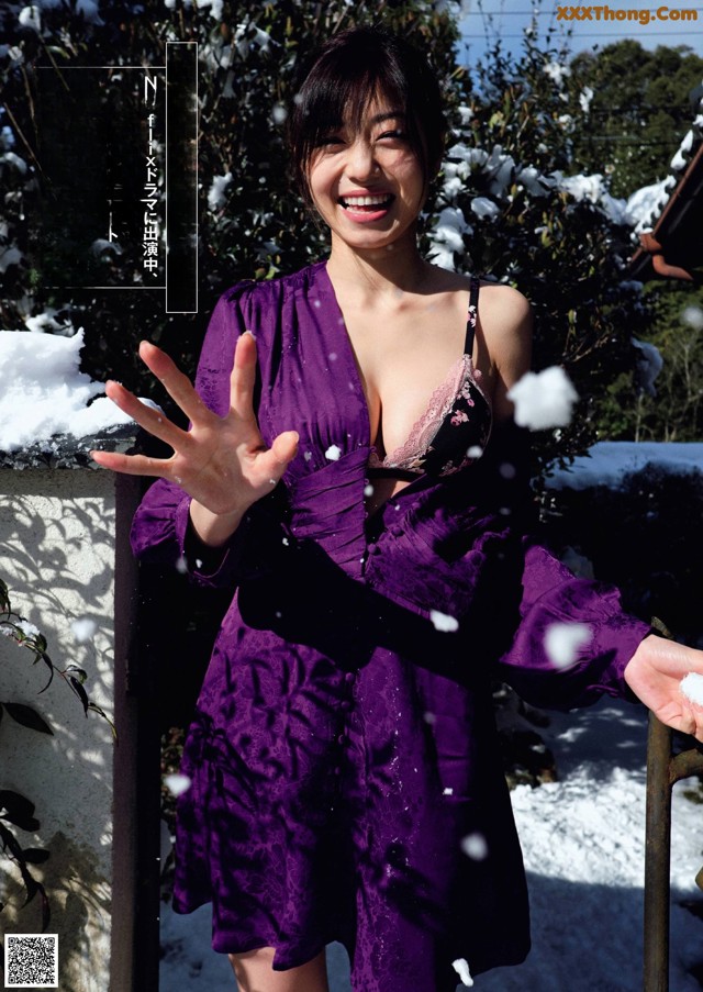 A woman in a purple dress standing in the snow.