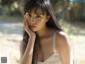 A woman leaning against a white door in a nude dress.