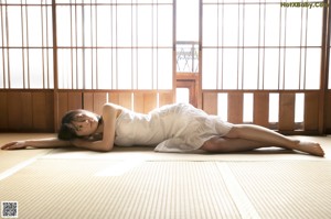 A woman in a white dress sitting on the floor.