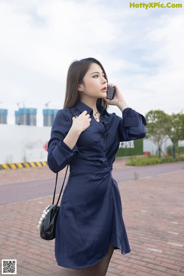 A woman in a blue dress talking on a cell phone.