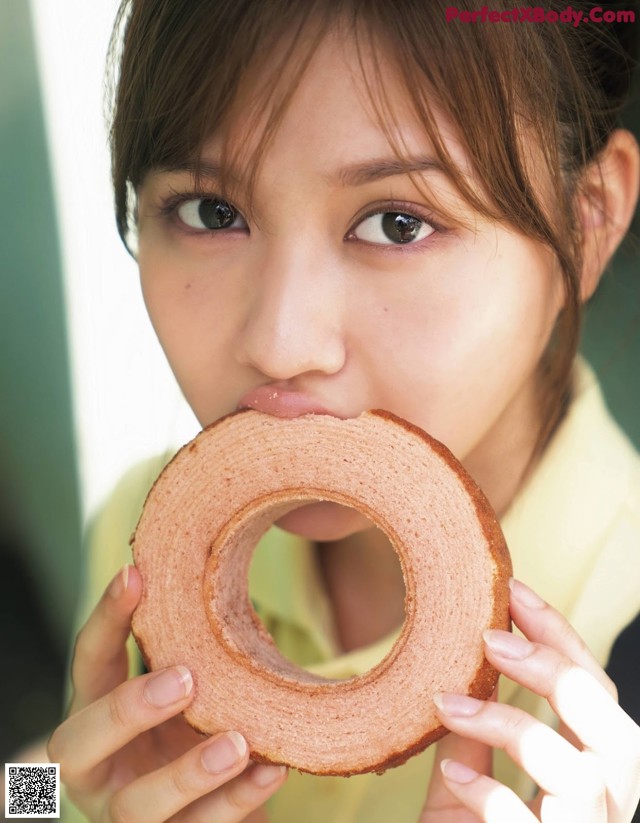 A woman holding a donut in front of her mouth.