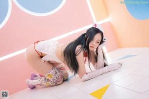 A woman in a nurse outfit sitting on the floor.