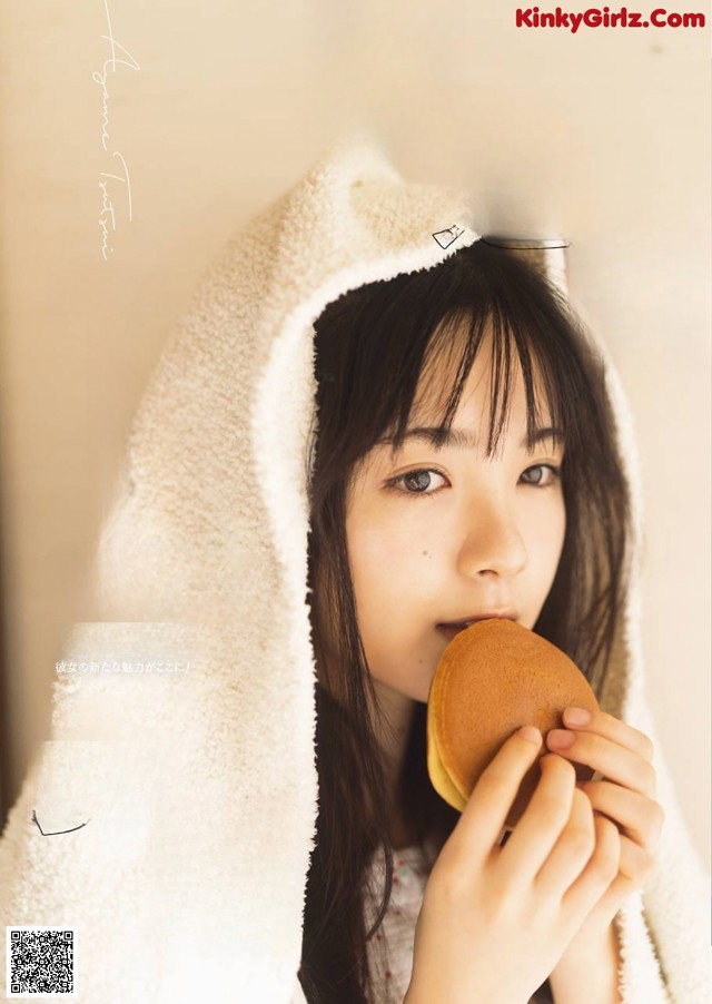 A woman in a towel holding a hamburger in her hand.