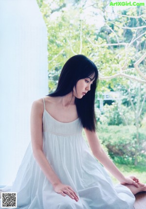 A woman in a white dress looking out of a window.