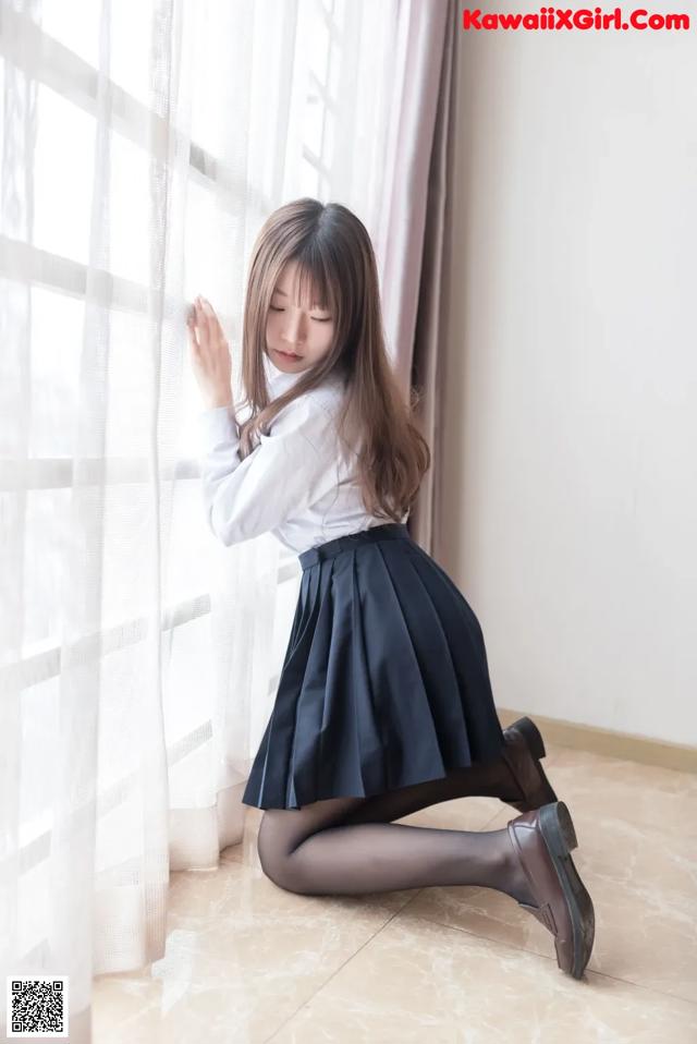 A woman in a white shirt and black skirt sitting on the floor.