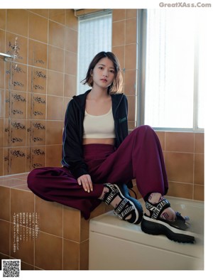 A woman in a blue shirt and black pants posing for a magazine.