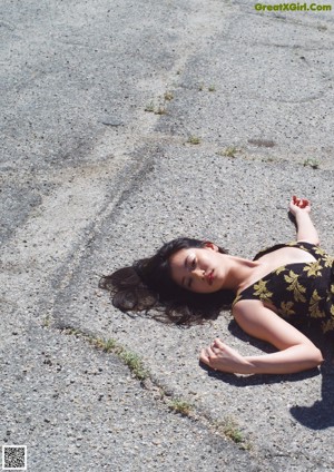 A woman laying on top of a roof next to a weather vane.