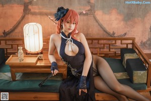 A woman in a black dress sitting on a wooden bench.