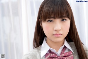 A young woman sitting on a couch wearing a school uniform.