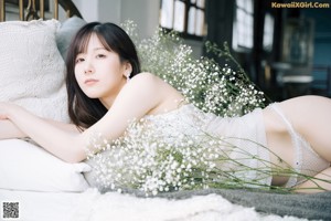 A woman laying on a couch surrounded by flowers.