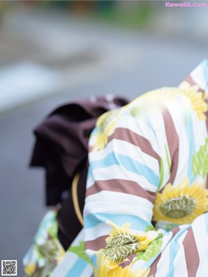 A woman wearing a sunflower kimono and a straw hat.