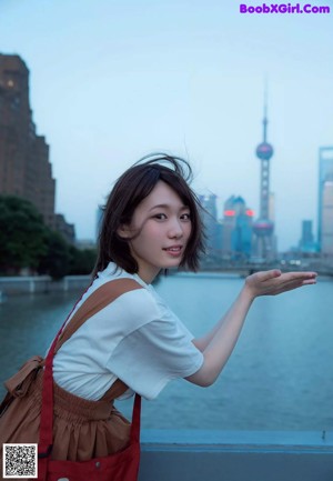 A woman in a floral dress waving at the camera.