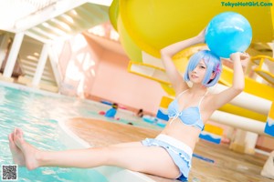 A woman in a blue bikini sitting on a white chair.