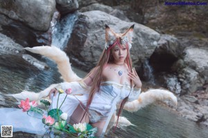 A woman in a white dress standing in the water with a fox.